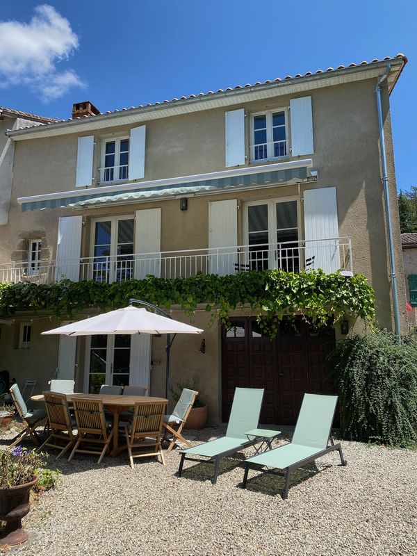 The back of the house in daylight, showing the outdoor dining area and sun loungers